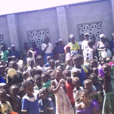 Orphans and elderly be side the hall we have constructed for their feeding program.